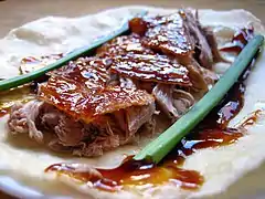 Le canard et les légumes d'accompagnement sont trempés dans la sauce, puis roulés dans une galette.