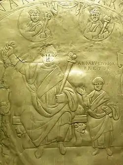 Photographie du fond d'un plat métallique comportant des figures de personnages gravées.