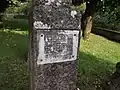 Plaque fixée sur une ancienne croix de pierre (XVIIe&nbsp;siècle) dans l'ancien cimetière.