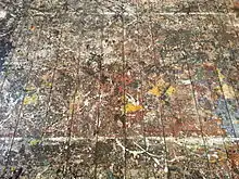Photographie en couleurs montrant des taches de peinture sur un plancher
