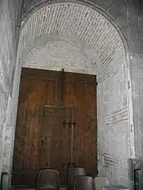 Porte encastrée sous une voute décrépite, montrant l'appareil en brique utilisé.