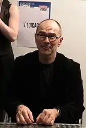 Homme assit derrière une table.