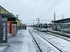 La station de Meyzieu Z.I. est à quatre voies. Les deux voies les plus au sud sont masquées par la rame Citadis du T3 qui quitte son terminus.