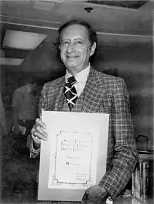 Photographie en noir et blanc d'un homme tenant une récompense.