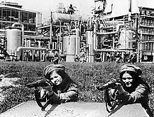 Photo en noir et blanc de deux femmes en uniforme militaire s'apprêtant à tirer au fusil.