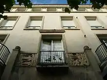 Immeuble construit vers 1947 à Royan par Claude Ferret, montrant les moulures aux formes classiques en pierre et les bas reliefs dans une tradition Art déco d'avant-guerre.