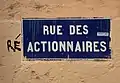 La même plaque de rue en 2019, accompagnée d'un tag sur le mur « Ré », formant l'allusion à « Réactionnaires », les partisans d'une politique prônant et mettant en œuvre un retour à une situation passée réelle ou fantasmée.