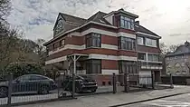 au no&nbsp;2, maison plurifamiliale, à trois habitations, de style moderniste, architecte Léon Smets, 1936. Construction non attenante à gauche, de deux niveaux sous toiture à croupes. Façades en briques, rehaussées d'éléments cimentés. Vers la rue, les trois travées s'avancent en saillies successives. Travée d'accès sur l'angle. La porte, à arc en plein cintre, a été dotée postérieurement d'un auvent à petits-fers. Troisième travée en ressaut, de trois niveaux sur garage. Travée centrale caractérisée par des fenêtres disposées sur l'angle.