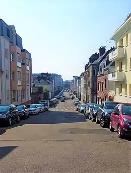 Cliché numérique couleur. Rue bordée d'immeubles d'habitation de trois étages du XXe&nbsp;siècle en enfilade.