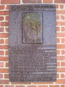 Plaque murale en métal ; de haut en bas : portrait de l'écrivain, texte de la loi.