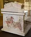 Vue d'un côté du sarcophage avec le côté de la base pourvue de fresques et un toit à double pente