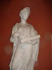 Statue grecque en pied d'une femme couronnée de lauriers, tunique drapée, un instrument en main (environ 50 cm).