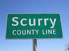 Panneau de signalisation routière, vert sur fond blanc, avec inscription Scurry county line.