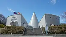 Photographie couleur d'un bâtiment moderne avec des drapeaux flottants au vent.