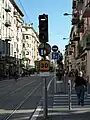 Image représentant un feu tricolore de tramway avec la barre horizontale marquant l’arrêt, le SAC avec losange orange indiquant la prise en charge de la priorité et le point d’exclamation bleu indiquant le passage à la barre verticale allumés, ainsi que la vitesse limitée à 30&nbsp;km/h à la station Palais des expositions.