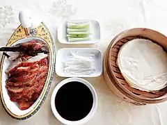 Canard laqué découpé et ses galettes cuites dans un cuiseur vapeur en bambou.