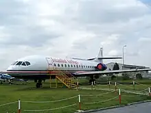 Photo en couleurs d'un avion vu du côté, à la livrée blanche, bleue et rouge, marqué « Istanbul Airlines ». Il est stationné sur un espace en herbe.