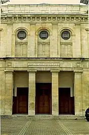 Vue d’un bâtiment de style néoclassique, de pierre jaune.