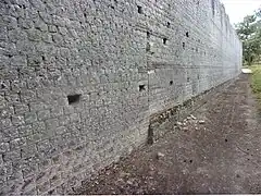 Photographie en couleurs d'un long mur avec une reprise de construction à mi-longueur