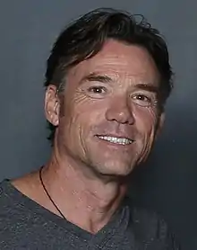 Un homme brun souriant.