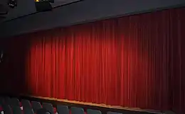 Rideau de tissu rouge formant des plis et masquant la scène.