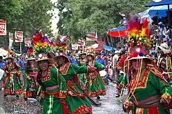 Danseuses de Tinku en costume traditionnel, durant une procession en Bolivie, photo annoncée dans la légende initiale comme prise au Carnaval d’Oruro (si ce n'est la présence des arbres, peu probable à 3&nbsp;710&nbsp;m, l'altitude d'Oruro).