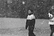 Photographie en noir et blanc d'un joueur de football, dans un paysage enneigé.