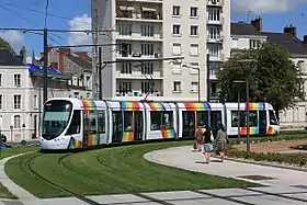 Photographie d'un tramway blanc et arc-en-ciel dans un virage.