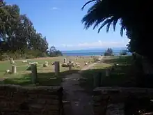 Vue de tronçons de colonnes antiques alignées sur une esplanade engazonnée.