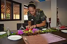 Une jeune volontaire en formation hotellerie-restauration dresse une table.