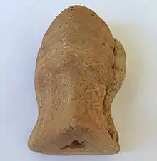 Bloc de terre-cuite de forme circulaire avec un côté arrondi et un côté avec un trou.