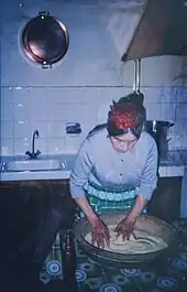 Grand-mère pied noire roulant la semoule dans une gasâa en noyer.