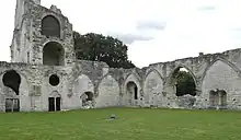 Deux pans de murs portant des arcs formerets au centre d'une pelouse et surmontés de l'abbatiale