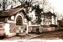 Vue de bâtiments du début du XXe&nbsp;siècle en bord de rue sur une carte postale ancienne.