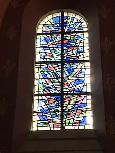 Vitrail abstrait composé de pièces de différentes couleurs (rouge, vert, bleu et jaune principalement).