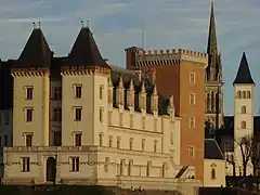 Photographie en couleurs d'une tour en brique rouge et d'une église.